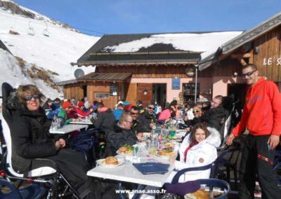Un groupe de vacanciers en situation de handicap et leurs accompagnateurs lors d'un repas en extérieur à la montagne