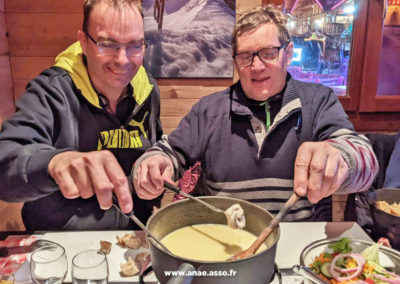 Deux vacanciers dégustent une fondue savoyarde dans un restaurant lors d'un séjour adapté handicap à Pralognan la Vanoise